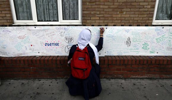 ‘런던 화재’ 희생자를 추모하는 메시지 쓰는 한 여성