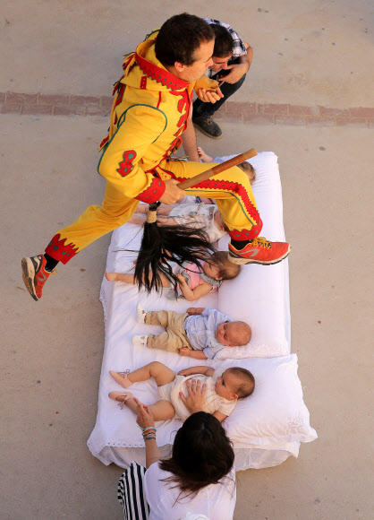 18일(현지시간) 스페인 부르고스 인근 카스트릴로 데 무르시아에서 열린 스페인 전통 의식인 ‘엘 콜라초(El Colacho)’에서 한 남성이 매트리스에 누워있는 아기들을 뛰어넘고 있다. 1620년부터 이어져오고 있는 이 의식은 악령 의상을 차려입은 남성이 생후 1년이 안된 아기들 위로 뛰어넘는 것으로 주민들은 악마를 내쫓고 아기들에게 축복이 내려진다고 믿는다.  AP 연합뉴스