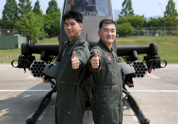 양성진(오른쪽) 준위와 아들 양한솔 준위가 육군 항공작전사령부 1항공여단 소속 공격헬기 AH1S ‘코브라’ 앞에서 엄지를 치켜세우며 포즈를 취하고 있다. 연합뉴스