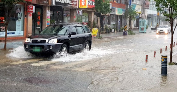 3일 오전 충북 옥천군 옥천읍 시가지 도로가 장맛비에 침수되면서 차량들이 거북이운행을 하고 있다.  연합뉴스