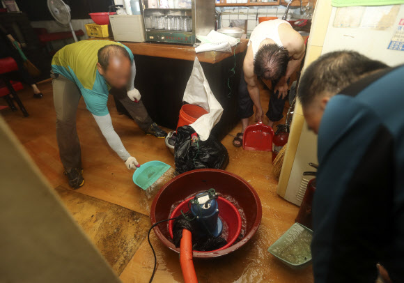 3일 오전 청주시 상당구의 한 음식점에 이날 내린 폭우로 물이 차면서 시민들이 양수기를 동원해 물을 빼내고 있다.  연합뉴스