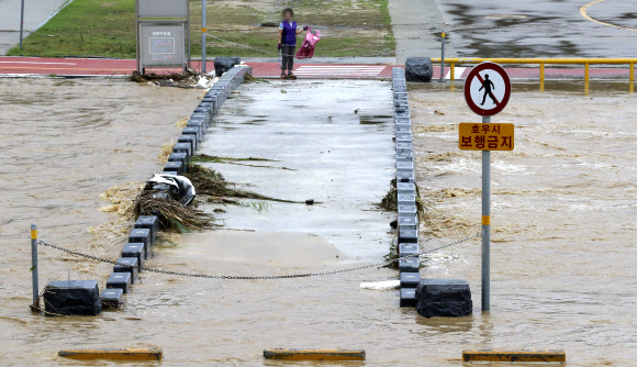 3일 오전 청주시 상당구 무심천이 범람해 시민들이 다리를 건너지 못하고 있다. 연합뉴스
