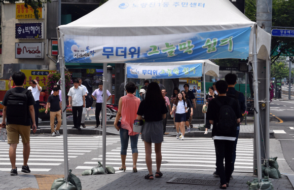 무더위가 찾아온 6일 서울 동작구 노량진의 한 횡단보도 섬에 설치된 그늘막 아래에서 시민들이 신호를 기다리고 있다. 이날 서울의 기온은 34.6도까지 치솟아 올 들어 가장 높은 수치를 보였다. 박지환 기자 popocar@seoul.co.kr