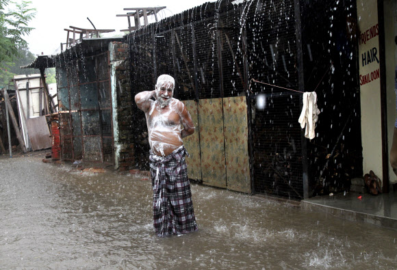 인도 우타르프라데시주 알라하바드에 폭우가 쏟아진 11일(현지시간) 한 남성이 몸에 비누칠을 하고 빗물에 샤워를 하고 있다. AP 연합뉴스