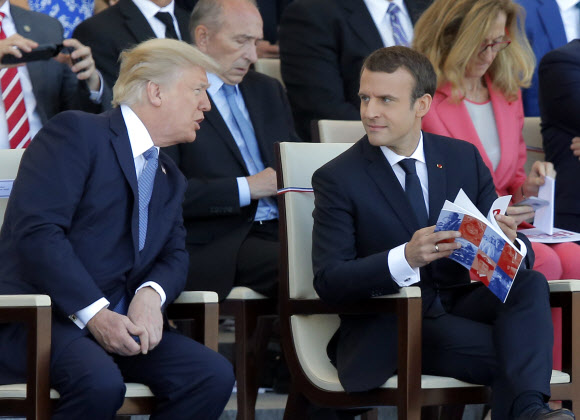 도널드 트럼프(왼쪽) 미국 대통령이 14일(현지시간) 프랑스 파리 샹젤리제에서 프랑스 혁명 기념일 열병식이 시작하기 전에 에마뉘엘 마크롱 프랑스 대통령과 이야기를 나누고 있다. AP 연합뉴스
