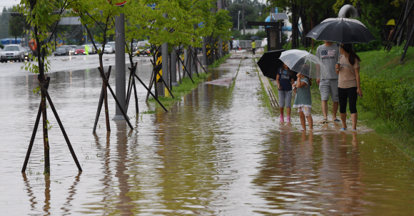 16일 충북 청주시 흥덕구에서 부모와 아이들이 물에 잠긴 인도를 지나고 있다. 290mm의 폭우가 내린 청주는 1995년 8월 이후 22년만에 홍수 피해를 입었다. 2017. 7. 16  청주=손형준 기자 boltagoo@seoul.co.kr