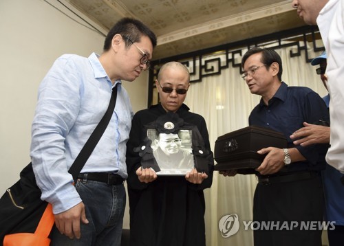 류샤오보의 부인 류샤(가운데)가 지난 15일 중국 랴오닝성 선양시 장례식장에서 남편의 영정 사진을 들고 슬퍼하고 있다.  선양 AP 연합뉴스