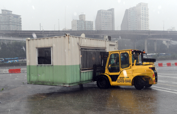 23일 서울 탄천주차장에서 갑작스럽게 내린 비로 침수이 우려가 있자 직원들이 컨테이너를 들어 높은지대로 옮기고 있다.  2017.9.23 박지환기자 popocar@seoul.co.kr