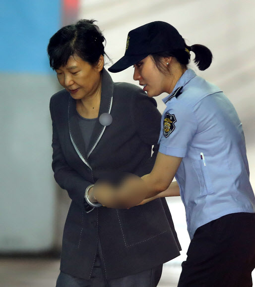 박근혜 전 대통령이 24일 오전 서울 서초동 서울중앙지법에서 열린 공판에 참석하기 위해 법원에 도착한 뒤 교도관의 손을 잡고 호송차에서 내리고 있다.  연합뉴스