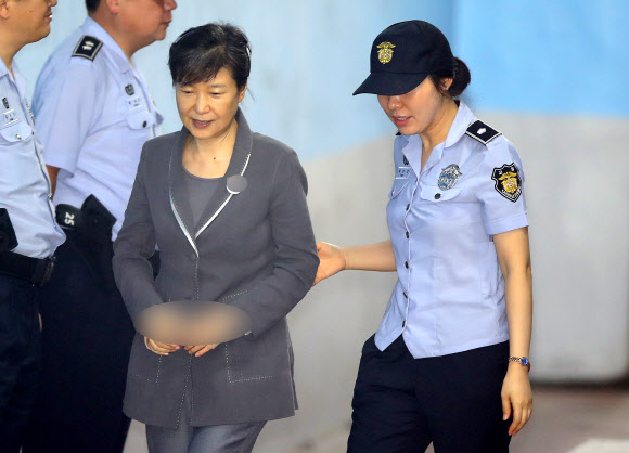 박근혜 전 대통령이 24일 오전 서울 서초동 서울중앙지법에서 열린 공판에 참석하기 위해 법원에 도착한 뒤 엷은 미소를 띄우며 교도관과 함께 구치감으로 향하고 있다.  연합뉴스
