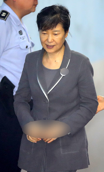 박근혜 전 대통령이 24일 오전 서울 서초동 서울중앙지법에서 열린 공판에 참석하기 위해 법원에 도착한 뒤 엷은 미소를 띄우며 교도관과 함께 구치감으로 향하고 있다.  연합뉴스