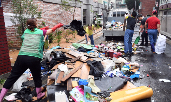24일 전날 폭우로 비피해를 입은 인천시 부평구 일대에서 자원봉사자들이 수해를 입은 물건들을 정리하고 있다.   정연호 기자 tpgod@seoul.co.kr