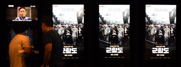 28일 서울 용산구 CGV용산아이파크몰에 있는 티켓발권기에 영화 ‘군함도’의 예고편이 나오는 가운데 영화관을 찾은 시민들이 영화 티켓을 사고 있다. 박지환 기자 popocar@seoul.co.kr