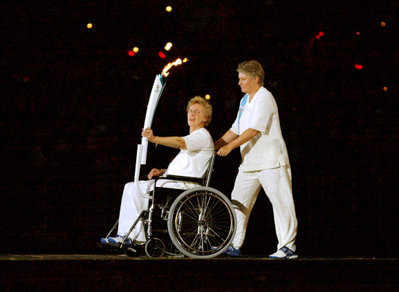 호주의 스프린터 전설 베티 커스버트(왼쪽)가 2000년 시드니올림픽 개회식 도중 성화 점화를 위해 다가가고 있다. 오른쪽 휠체어를 미는 이는 올림픽 스프린터 출신이며 오랜 친구인 릴렌 보일. AFP 자료사진 연합뉴스