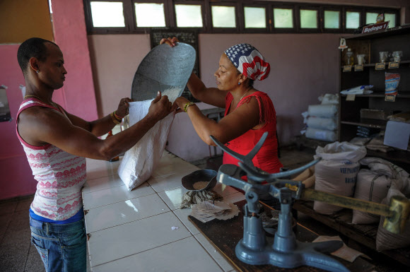 2년 전 미국과의 국교를 회복했지만 여전히 물자가 부족한 쿠바에 미국·유럽 관광객들이 밀려 들어오면서 현지 주민들은 생필품조차 구하지 못하는 상황에 놓였다. 사진은 지난 6월 20일 쿠바 산티아고 산루이스의 한 쌀가게에서 주민이 쌀을 사고 있는 모습. 산루이스 AFP 연합뉴스