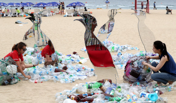 13일 부산 해운대구 해운대해수욕장에 그린피스 활동가들이 일회용 플라스틱을 이용해 만든 미술작품을 통해 여름철 피서지에 버려지는 쓰레기에 대한 경각심을 일깨우는 퍼포먼스를 펼치고 있다. 그린피스는 이날부터 사흘간 해수욕장에서 시민들을 대상으로 일회용 플라스틱 소비를 줄이는 캠페인을 진행한다.  연합뉴스