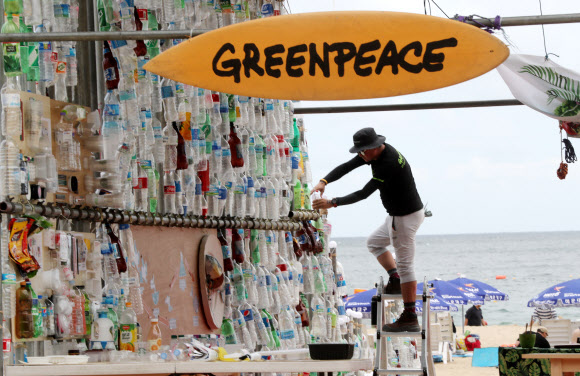 13일 부산 해운대구 해운대해수욕장에서 그린피스 활동가들이 일회용 플라스틱으로 파괴되는 환경을 표현하는 예술작품을 설치하고 있다. 그린피스는 이날부터 사흘간 해수욕장에서 시민들을 대상으로 일회용 플라스틱 소비를 줄이는 캠페인을 진행한다.  연합뉴스