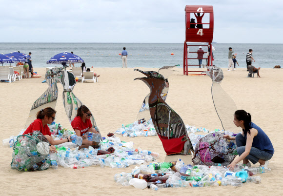 13일 부산 해운대구 해운대해수욕장에서 그린피스 활동가들이 일회용 플라스틱으로 파괴되는 환경을 표현한 예술작품을 통해 퍼포먼스를 펼치고 있다. 그린피스는 이날부터 사흘간 해수욕장에서 시민들을 대상으로 일회용 플라스틱 소비를 줄이는 캠페인을 진행한다.  연합뉴스