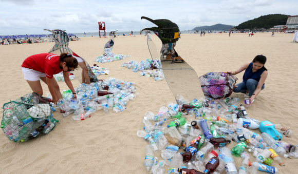 13일 부산 해운대구 해운대해수욕장에서 그린피스 활동가들이 일회용 플라스틱으로 파괴되는 환경을 표현한 예술작품을 통해 퍼포먼스를 펼치고 있다. 그린피스는 이날부터 사흘간 해운대해수욕장에서 시민들을 대상으로 일회용 플라스틱 소비를 줄이는 캠페인을 진행한다.  연합뉴스