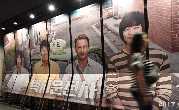 5.18 광주민주화운동을 소재로 한 영화 ’택시운전사’가 누적관객수 천만을 돌파해 올해 첫 ’천만 영화’로 기록된 20일 서울 용산의 한 영화관에서 관람객들이 ’택시운전사’ 포스터 앞을 지나가고 있다. 2017. 8. 20. 박윤슬 기자 seul@seoul.co.kr