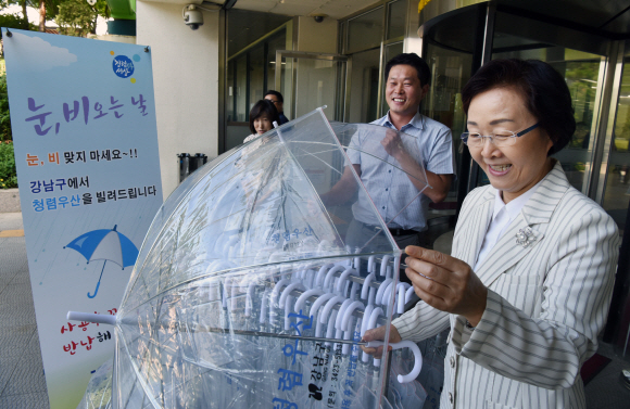 신연희 서울 강남구청장이 지난 25일 청사 로비에서 누구나 공짜로 빌리고 양심껏 반납하는 ‘청렴우산’을 직원들과 살펴보고 있다. 이종원 선임기자 jongwon@seoul.co.kr