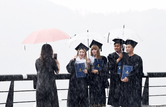 최근 대학가 졸업식이 한창인 가운데 졸업식이 과거에 비해 크게 간소화되고 있다. 사진은 지난 23일 서울 종로구 상명대에서 열린 후기 졸업식에서 졸업생들이 우산을 쓴 채 기념촬영을 하고 있는 모습. 도준석 기자 pado@seoul.co.kr