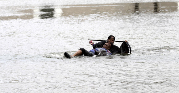 초강력 허리케인 ‘하비’가 27일(현지시간) 미국 텍사스주 휴스턴을 강타한 가운데 한 남성이 물에 빠진 여성을 구하고 있다. AP 연합뉴스