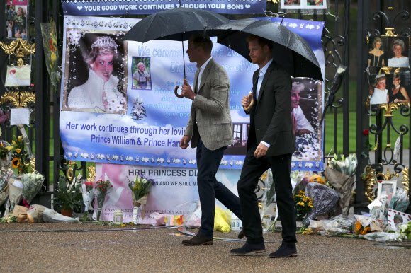 윌리엄(왼쪽) 영국 왕세손과 해리 왕자가 어머니 다이애나 왕세자비의 20주기를 하루 앞둔 30일(현지시간) 다이애나가 생전에 살았던 런던 켄싱턴궁 앞에 일반인들이 마련한 추모공간을 바라보며 지나가고 있다. 런던 AFP 연합뉴스