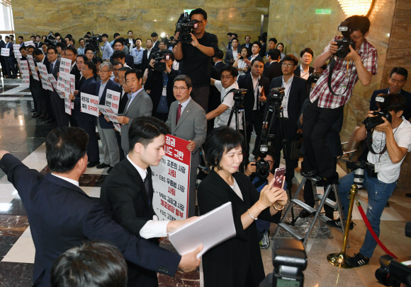 손혜원 더불어민주당 의원이 4일 오전 국회 본회의장 입구 로텐더홀에서 MBC 김장겸 사장 체포영장에 항의해 국회 본회의를 보이콧하고 피켓팅하고 있는 자유한국당 의원들의 모습을 핸드폰으로 촬영하자 자유한국당 의원들이 항의와 야유를 보내고 있다.  2017.09.04 강성남 선임기자 snk@seoul.co.kr
