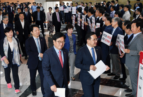 우원식 더불어민주당 원내대표와 소속의원들이 4일 오전 서울 여의도 국회 로텐더홀에서 MBC김장겸 사장에 대한 체포영장을 정권의 공영방송 장악 의도라 규탄하며 본회의를 보이콧하고 피켓팅을 하고 있는 자유한국당 의원들을 지나 본회의장으로 들어가고 있다.  2017.09.04 강성남 선임기자 snk@seoul.co.kr