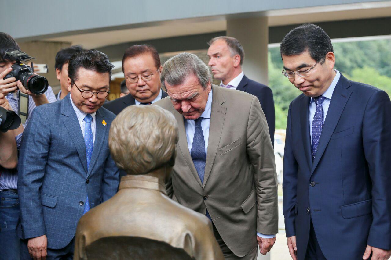 양기대(오른쪽) 광명시장이 지난 11일 고 이순덕 할머니 흉상 앞에서 한국에서 최초로 위안부 피해 증언을 하신 분이라고 설명하자 게르하르트 슈뢰더(가운데) 전 독일총리가 추모 목례를 하고 있다. 광명시 제공 
