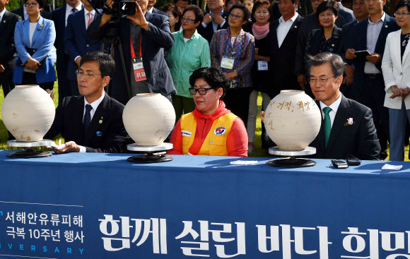 문재인 대통령이 15일 오후 충남 태안군 만리포해수욕장 일원에서 열린 ‘함께 살린 바다 희망으로 돌아오다’ 서해안유류피해 극복 10주년 행사, 유류 피해 극복기념관 개관식에 참석해 개관 세리머니로 희망 항아리에 메시지를 남기고 있다.연합뉴스