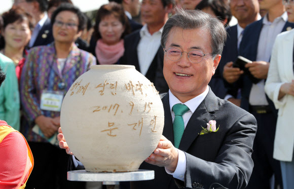 문재인 대통령이 15일 오후 충남 태안군 만리포해수욕장 일원에서 열린 ‘함께 살린 바다 희망으로 돌아오다’ 서해안유류피해 극복 10주년 행사, 유류 피해 극복기념관 개관식에 참석해 개관 세레머니로 희망 항아리에 메시지를 남기고 있다.연합뉴스.