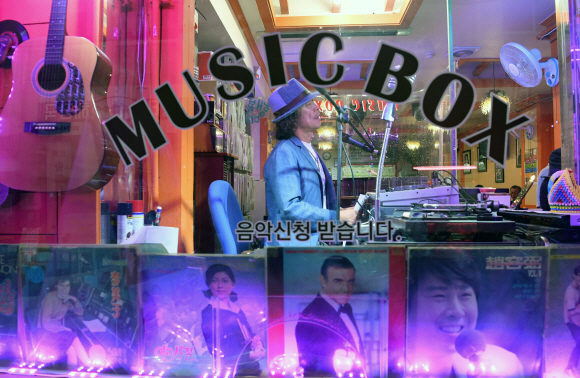 DJ 장민욱씨가 거리에서 보이는 음악감상실 뮤직박스에서 손님들의 음악신청 사연을 소개하고 있다.