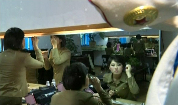 북한 조선중앙TV가 15일 공개한 영상에서는 지방순회 공연에 나선 모란봉악단 예술인들이 신의주에서의 공연을 앞두고 분장실에서 메이크업하는 모습이 등장했다. 사진은 거울을 보며 눈썹과 아이라인을 그리고 있는 여가수들의 모습.  연합뉴스