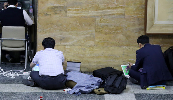 2017년 국정감사가 중반으로 들어선 19일 오전 국회 한 상임위원회 국감장 인근 차가운 바닥에 피감기관 관계자가 앉아 자료를 준비하고 있다. 매년 국회 국정감사 기간에는 피감기관이 몰려 상임위원회 인근 복도에 마련된 간이 사무공간(70여석)의 자리가 부족해 피감기관 관계자들이 아침부터 자리 잡기에 나서고 있다. 연합뉴스