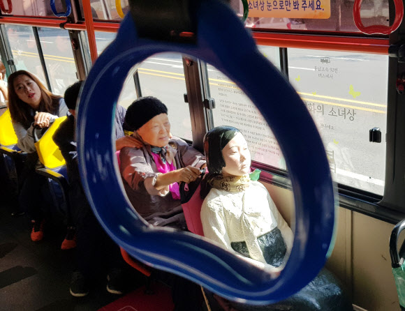 19일 오전 경기도 수원시 권선구 92번 시내버스에서 일본군 위안부 피해자 안점순(89) 할머니가 버스에 탄 ’평화의 소녀상’을 어루만지고 있다.  연합뉴스