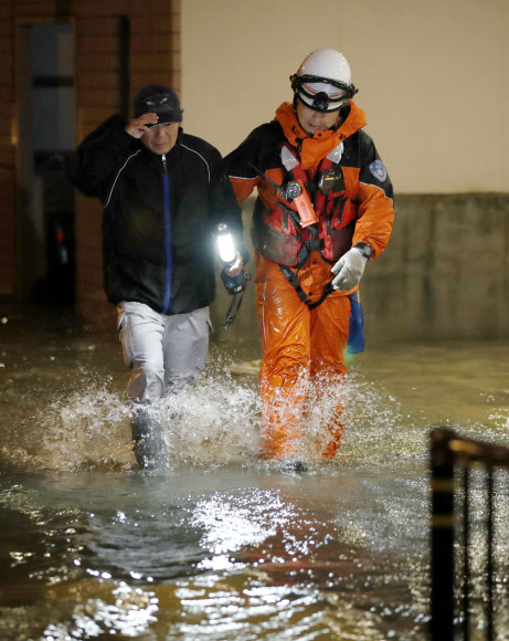 제21호 태풍 ’란’이 일본 열도를 강타한 가운데 23일 새벽 일본 오사카(大阪)부 사카이(堺)시의 침수된 도로에서 한 남성이 구급대원의 도움으로 대피하고 있다.  교도=연합뉴스
