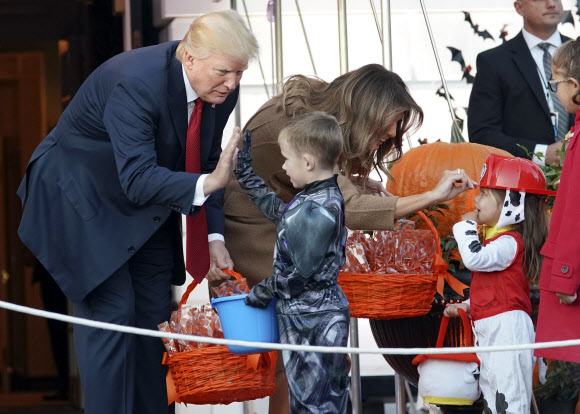도널드 트럼프 미국 대통령과 멜라니아 여사가 30일(현지시간) 핼러윈데이를 맞아 백악관을 찾은 워싱턴 지역 및 미군 가족 어린이들에게 사탕을 나눠주고 있다. AP 연합뉴스