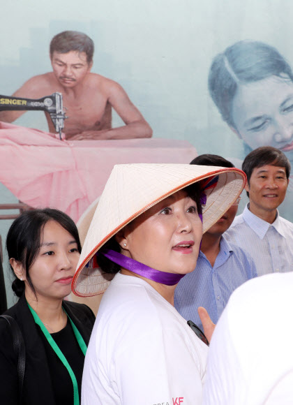 문재인 대통령 부인 김정숙 여사가 베트남 전통 모자인 ’논라’를 쓰고 10일 오후 베트남 땀끼시 땀따잉 벽화마을을 방문, 마을의 이야기가 담긴 벽화를 살펴보고 있다. 땀따잉 벽화마을은 지난해 6월 한국과 베트남이 공동으로 완성했으며 한국의 공공미술 작가, 자윈봉사자, 마을 주민들이 힘을 모아 120여 가구의 벽면과 담장을 칠하고 벽화를 그린 한국식 벽화마을이다.  연합뉴스