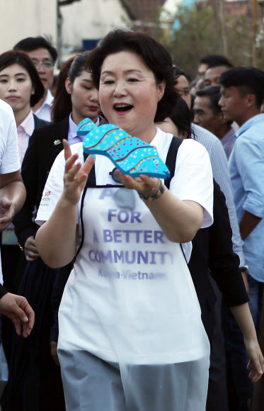 문재인 대통령 부인 김정숙 여사가 10일 오후 베트남 땀끼시 땀타잉 벽화마을을 방문, 벽화에 들어갈 물고기 모양의 타일을 직접 만들어 벽으로 가져가고 있다. 땀타잉 벽화마을은 지난해 6월 한국과 베트남이 공동으로 완성했으며 한국의 공공미술 작가, 자원봉사자, 마을 주민들이 힘을 모아 120여 가구의 벽면과 담장을 칠하고 벽화를 그린 한국식 벽화마을이다.  연합뉴스