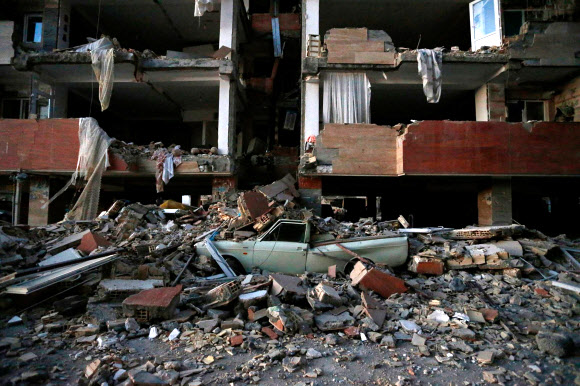 13일(현지시간) 이란 북서부 케르만샤주 사르폴-에자하브 마을에서 차량 한 대가 지진으로 무너져 내린 건물 잔해에 깔려 있다. AFP 연합뉴스