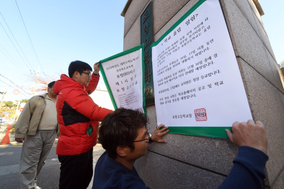 16일 수능시험장인 경북 포항시 포항고등학교에서 교직원들이 수능연기 안내문을 붙이고 있다. 2017. 11. 16  정연호 기자 tpgod@seoul.co.kr