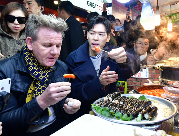 영국 출신의 세계적인 셰프인 고든 램지(왼쪽)가 지난 18일 서울 종로구 광장시장을 찾아 떡볶이를 맛보고 있다. 연합뉴스