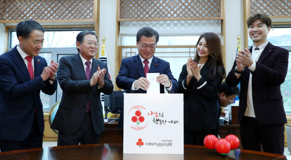 문재인 대통령이 20일 오후 청와대 여민관 집무실에서 사회복지공동모금회 사랑의열매 전달식을 하고  모금함에 성금을 넣고 있다. 왼쪽부터 박능후 보건복지부 장관, 허동수 사회복지공동모금회 회장, 문 대통령, 배우 채시라, 개그맨 박수홍. 연합뉴스