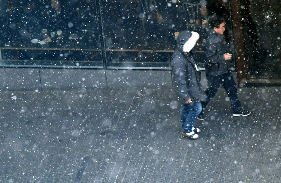 본격적인 겨울의 시작을 알리는 눈이 내린 20일 오후 서울 종로구에서 시민이 함박눈 속을 걷고 있다.  연합뉴스