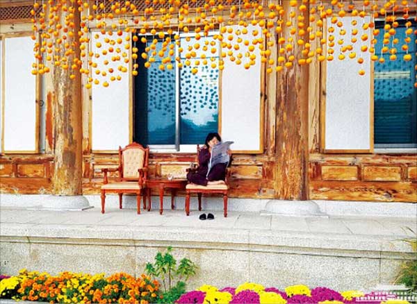 문재인 대통령의 부인 김정숙 여사가 청와대 관저 처마에 달아 놓은 곶감 줄 아래에서 편안한 복장으로 신문을 읽는 사진이 지난 4일 청와대 인스타그램에 공개됐다. 김 여사는 최근 청와대 감나무에서 딴 감을 직접 깎아 줄에 하나씩 꿰었다고 청와대 측은 설명했다. 청와대 인스타그램