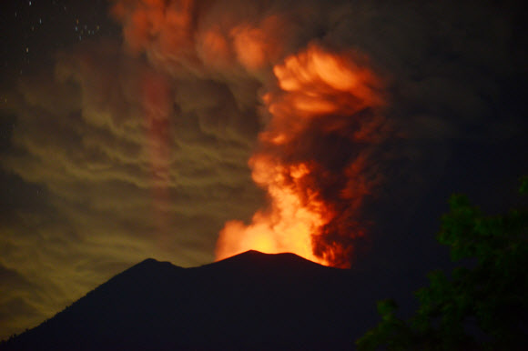 인도네이사 발리섬의 최고봉인 아궁 화산이 28일(현지시간) 거대한 화산재를 뿜어내는 가운데 정상 분화구가 붉게 물들어 있다. AFP 연합뉴스