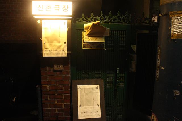 신촌극장은 서울 서대문구 창천교회 근처의 한 연립주택 4층 옥탑에 있다. 작은 간판과 포스터가 붙어 있는 현관 입구.