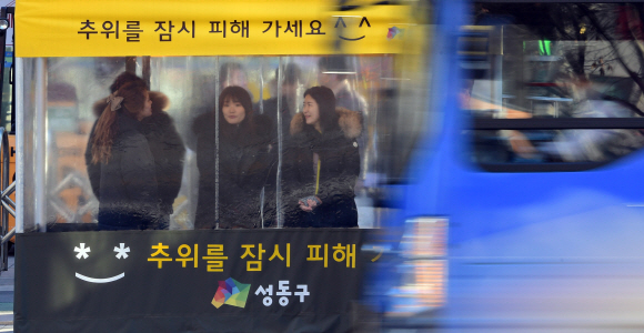 추위가 맹위를 떨친 13일 서울 성동구청 앞 버스정류장에 설치된 추위대피소’온기누리소’에서 시민들이 추위를 피하며 버스를 기다리고 있다. ’온기누리소’는 성동구가 버스정류장에 설치한 추위대피소로 현재  17개가 설치되어 있고 앞으로 11개가 추가로 설치될 예정이다. 2017. 12. 13 정연호 기자 tpgod@seoul.co.kr